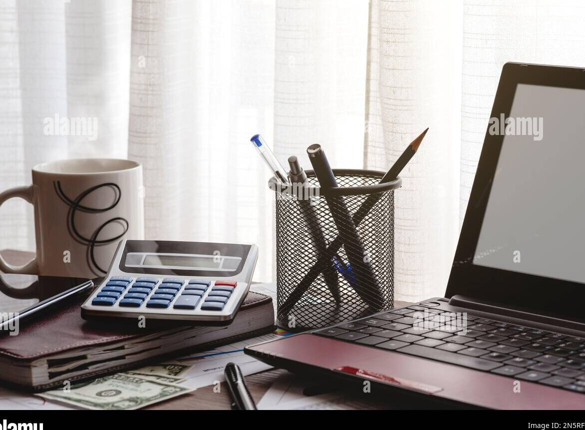 una imagen de un escritorio con un ordenador portatil una agenda y boligrafos