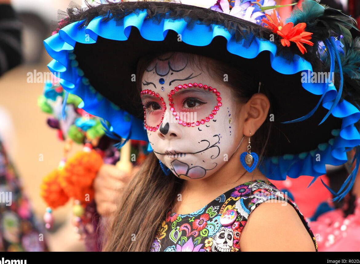 una imagen de un nino y una nina vestidos con trajes coloridos de dia de muertos rodeados de calaveras decoradas y flores brillantes
