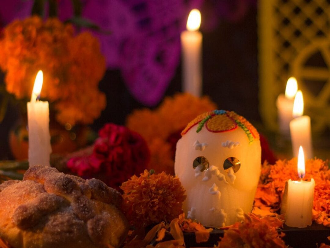 una imagen de una ofrenda tradicional de dia de muertos con velas flores de cempasuchil y alimentos
